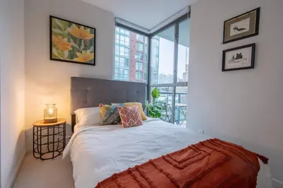 a bedroom with a bed and a large window at Heart of Downtown King Suite/Parkng/Pool/Gym/Sauna in Vancouver