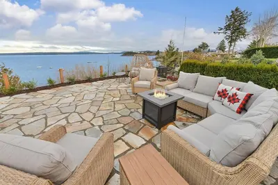 a patio with couches and a table and the water at The Beach House Suite by EMR Vacation Rentals in Chemainus