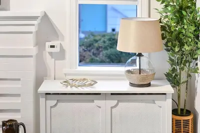 a lamp on a white table next to a window at The Beach House Suite by EMR Vacation Rentals in Chemainus