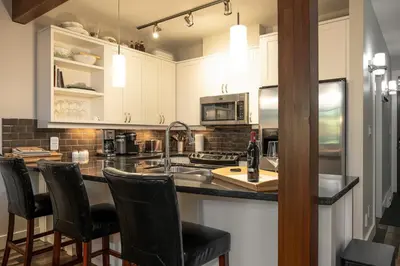 a kitchen with white cabinets and black counter tops at Pacific Forest Beach House in Parksville