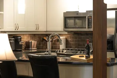a kitchen with a sink and a stove and microwave at Pacific Forest Beach House in Parksville