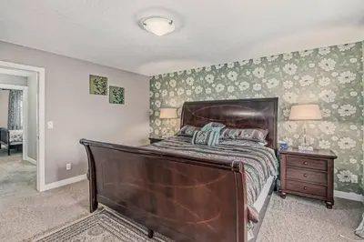 a bedroom with a large bed and a night stand at Luxury 4 Bedroom Cozy Home close to YYC, Shops, DT, Stampede, Mountains and many amenities in Panorama Hills NW Calgary in Calgary