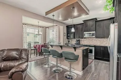 a kitchen with a bar and a living room at Luxury 4 Bedroom Cozy Home close to YYC, Shops, DT, Stampede, Mountains and many amenities in Panorama Hills NW Calgary in Calgary