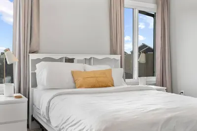 a bedroom with a large white bed with a window at Cozy Home - 9mins to WEM -Foosball -Vintage arcade - Air conditioning in Edmonton