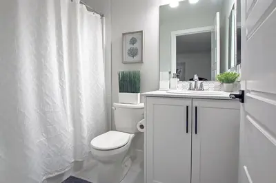 a white bathroom with a toilet and a sink at Beautiful 3Bed-with AC-Close to Spruce Meadows & Mountains in Calgary