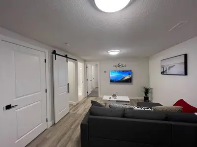 a living room with a black couch and a table at Cozy New Suite in NW Calgary in Calgary