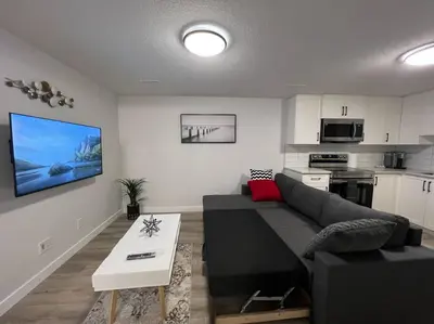 a living room with a couch and a kitchen at Cozy New Suite in NW Calgary in Calgary
