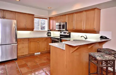 a kitchen with wooden cabinets and a stainless steel refrigerator at Villas at Eldorado Resort in Kelowna