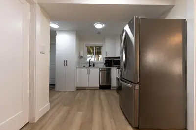 a stainless steel refrigerator in a kitchen with white cabinets at Guest Suite steps away from parks, trails & transit. in Port Coquitlam