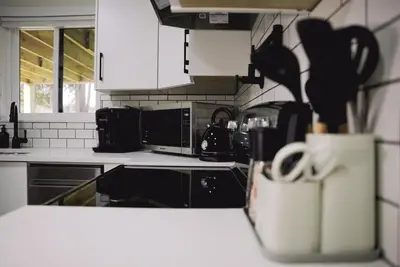 a kitchen with black and white appliances and a bag of utensils at Guest Suite steps away from parks, trails & transit. in Port Coquitlam