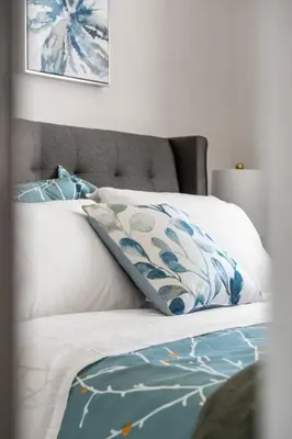a white bed with blue and white pillows on it at Stylish 3BR Townhouse by Airport in Calgary