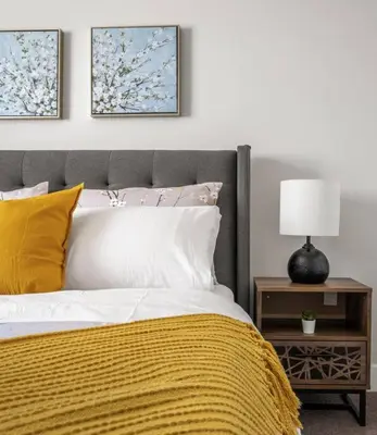 a bed with a yellow blanket and a table with a lamp at Stylish 3BR Townhouse by Airport in Calgary