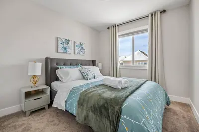 a white bedroom with a bed and a window at Stylish 3BR Townhouse by Airport in Calgary