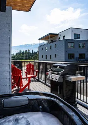a balcony with a grill and chairs and a building at Switchback Suite by Revelstoke Vacations in Revelstoke