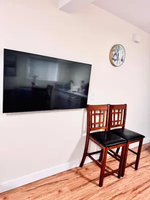 a chair sitting in a room with a clock on a wall at Cozy 2 beds Spacious rooms,Close to transit in Vancouver