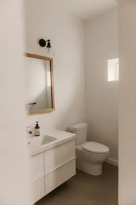 a white bathroom with a toilet and a mirror at Drift West Coast Getaway in Ucluelet