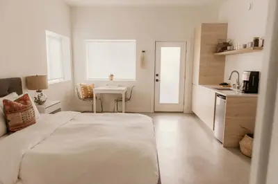 a white bedroom with a bed and a table at Drift West Coast Getaway in Ucluelet