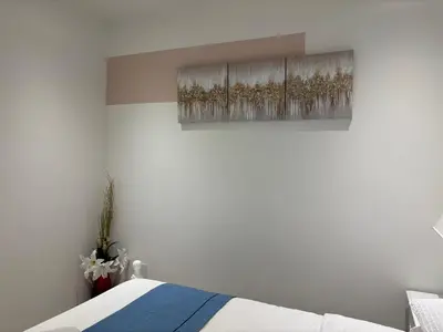a white bedroom with a bed and a painting on the wall at Fancy Family Suite with Parking near UBC in Vancouver