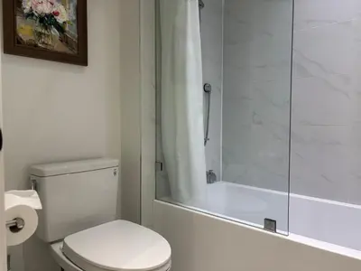 a bathroom with a toilet and a glass shower at Fancy Family Suite with Parking near UBC in Vancouver