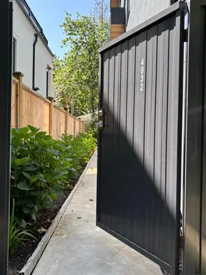 a black fence with a black door on a sidewalk at Fancy Family Suite with Parking near UBC in Vancouver