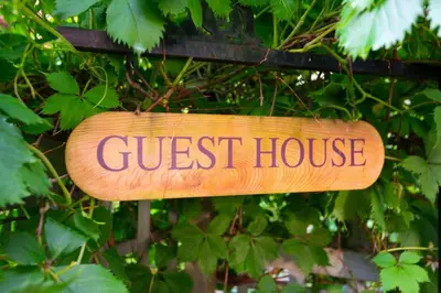 a sign that reads guest house hanging on a bush at Caboose in Bowen Island