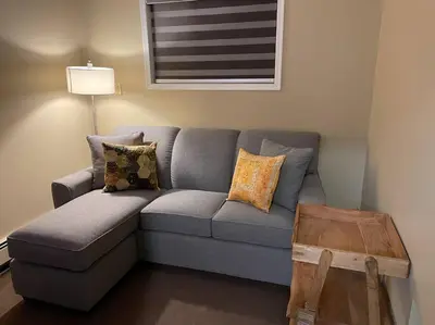 a gray couch in a living room with a table at Cozy Furnished Apartment in Simpson