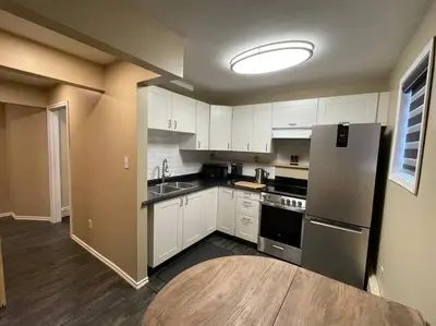 a kitchen with white cabinets and a stainless steel refrigerator at Cozy Furnished Apartment in Simpson
