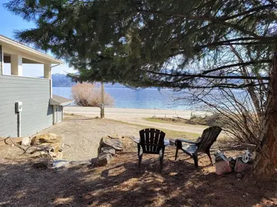 two chairs sitting under a tree next to a house at Lakeview B&B in Peachland
