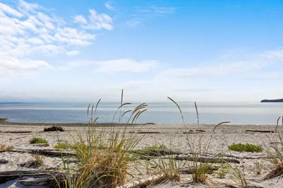 a beach with some grass and the ocean at Beachfront Luxury Suite #18 at THE BEACH HOUSE in Campbell River