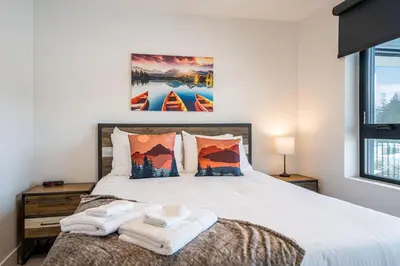 a bedroom with a large bed with towels on it at Alpine Dream by Revelstoke Vacations in Revelstoke