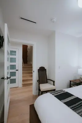 a white bedroom with a bed and a chair at A Gentle Hideaway in the Urban Forest WEST END downtown Vancouver in Vancouver