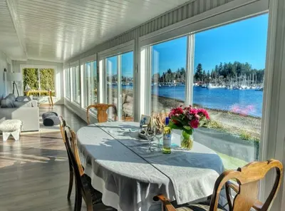 a dining room with a table with a view of the water at The Beach House at Deep Bay in Bowser