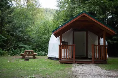 a tent and a picnic table in a field at Revelstoke RV & Cabin Resort in Revelstoke