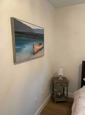 a painting of a boat on a wall next to a table at Adorable 1 Bedroom Suite- a skip to Galloping Goose in Victoria