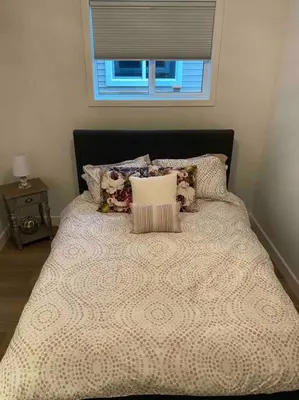 a bed with a black head board with pillows and a window at Adorable 1 Bedroom Suite- a skip to Galloping Goose in Victoria