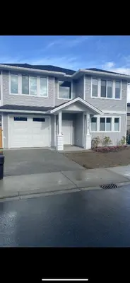 a large house with white garage doors on a street at Adorable 1 Bedroom Suite- a skip to Galloping Goose in Victoria