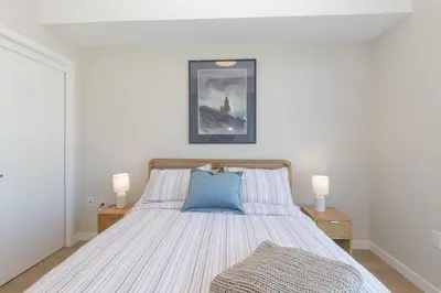 a bedroom with a bed with a blue pillow on it at Live The Dream In The Haro in Saanichton