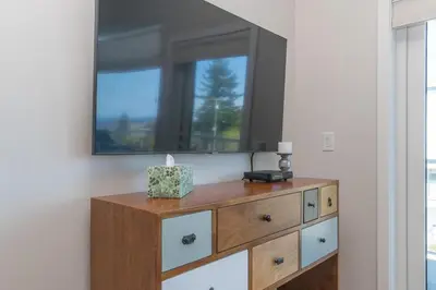a wooden dresser with a mirror on a wall at Live The Dream In The Haro in Saanichton