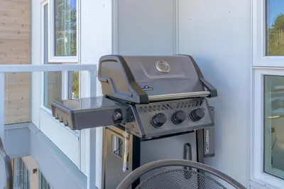 a grill sitting on a porch next to a window at Live The Dream In The Haro in Saanichton