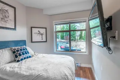 a bedroom with a bed and a tv and a window at Fabulous Condo at Five Star Resort 209 in West Kelowna