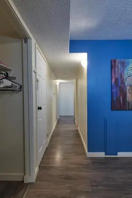 an empty hallway with blue walls and wooden floors at Bowness Suites in Calgary