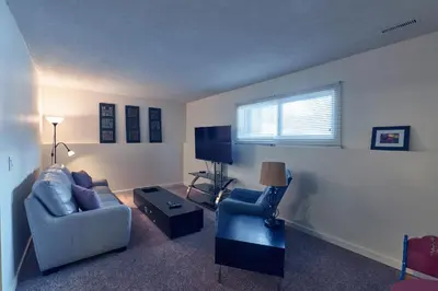 a living room with a couch and two chairs and a tv at Bowness Suites in Calgary