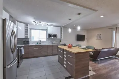 a kitchen with a refrigerator and a table in it at Bowness Suites in Calgary