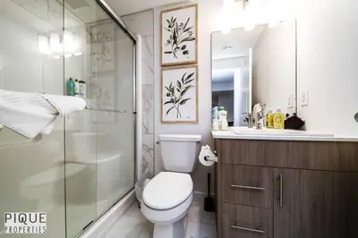 a bathroom with a shower and a toilet and a sink at *NEW* Modern Suite King Bed! Netflix! Sleeps 4! in Edmonton