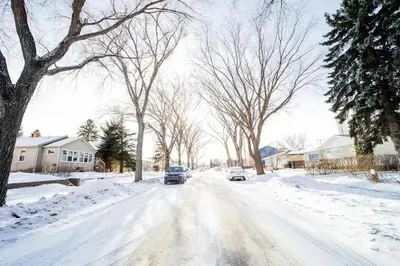 a snow covered street with cars driving down it at Cozy 3 Bedroom Contemporary Home With Free Parking in Edmonton