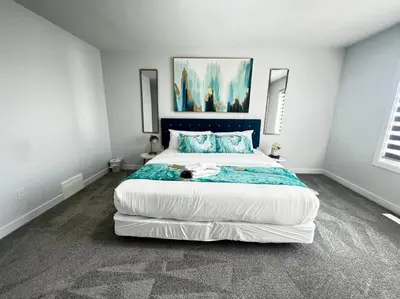 a bedroom with a large bed with a cat laying on it at Gorgeous 6BR New Home for Families in Nisku