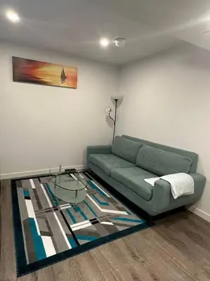 a living room with a green couch and a glass table at Brand new 1 Bedroom Basement Suite. Wi-Fi,Netflix in Edmonton