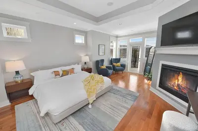 a bedroom with a white bed and a fireplace at Mount Finlayson View Villa by EMR Vacation Rentals in Victoria