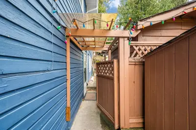 a wooden pergola on the side of a blue building at Luxury Delta 2BD Suit on ground floor in Delta