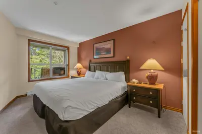 a bedroom with a large bed and a window at Best ski in ski out condo #3 in Aspens in Whistler